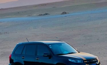 A black SUV with yellow racing stripes parked on desert terrain at sunset, showcasing Thutmoses Tours' adventurous desert excursions and travel experiences.