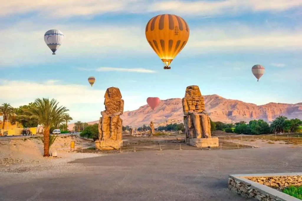 Hot air balloon flying over the Colossi of Memnon in Luxor.