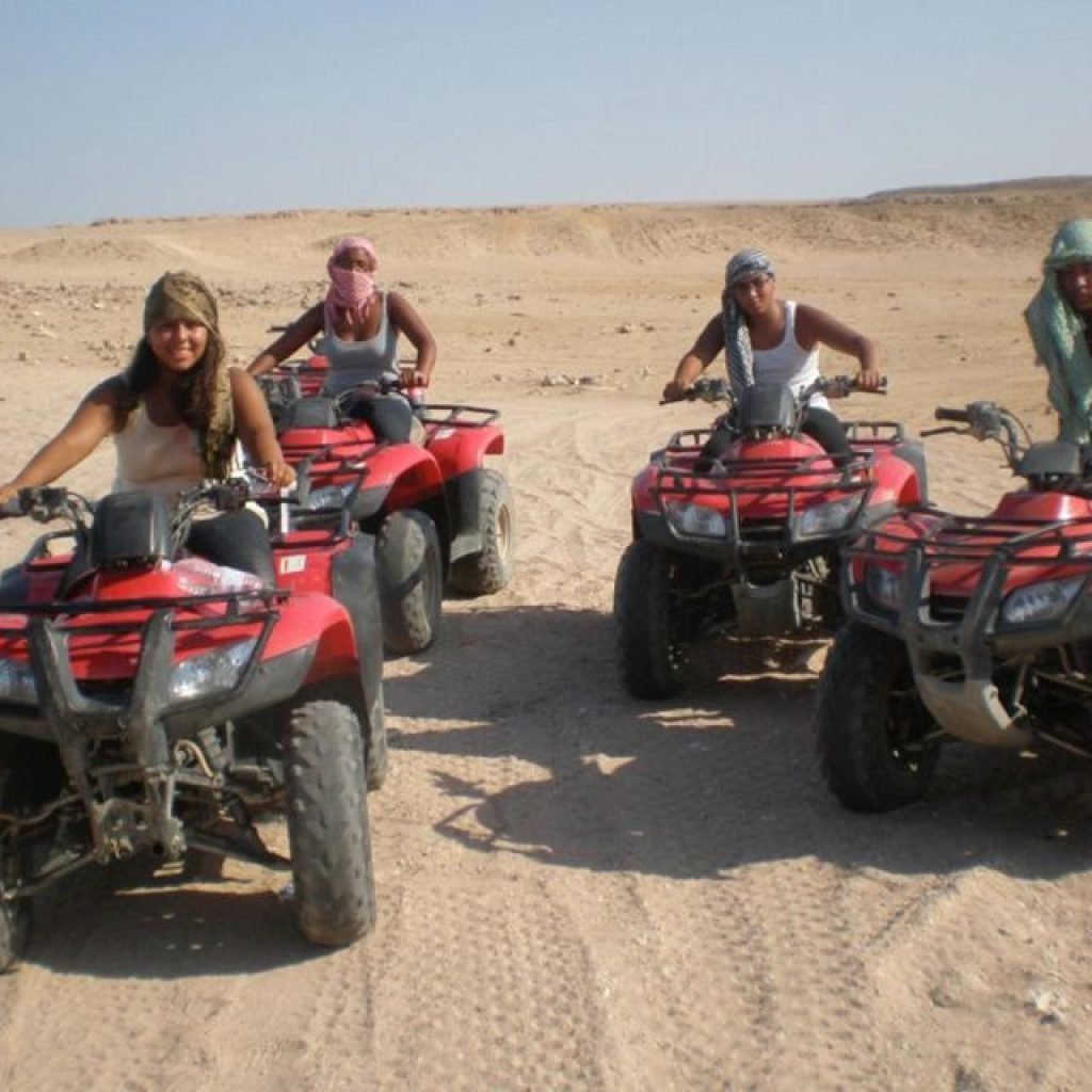 Quad bikes parked in Luxor’s Eastern Desert near palm trees, ready for safari adventure.